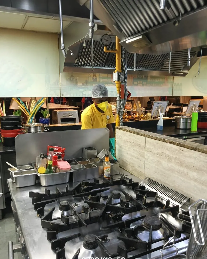 Safe Home Pestochem technician: applying gel bait under the cooking range in a hotel kitchen